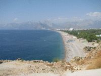 Vaizdas nuo stataus šlaito kur matosi jūros pakrantė ir kalnų siluetas Antalijoje